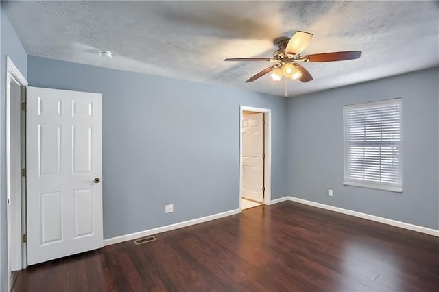 spare room featuring dark wood-type flooring, a textured ceiling, and ceiling fan