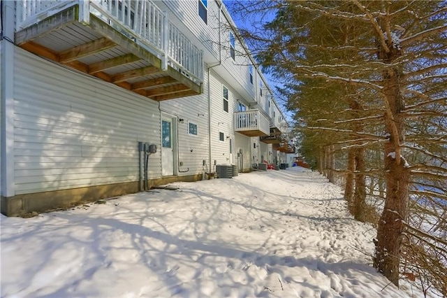 snow covered property with central AC and a balcony