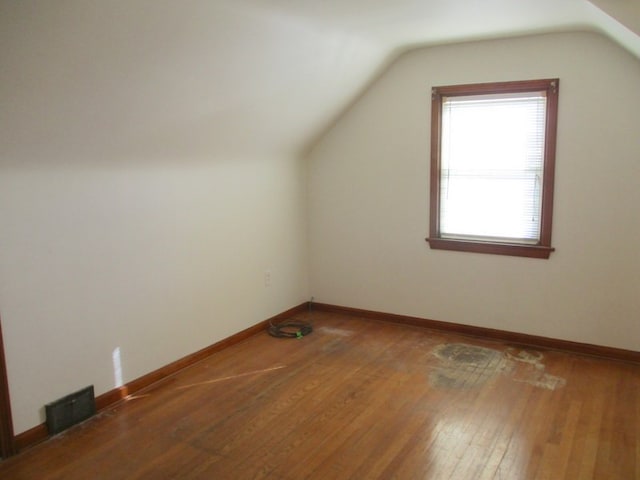 additional living space with hardwood / wood-style floors and vaulted ceiling