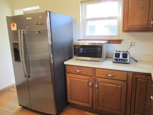 kitchen with appliances with stainless steel finishes and light hardwood / wood-style floors