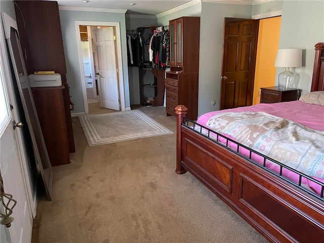 bedroom featuring ornamental molding, ensuite bath, light carpet, and a closet