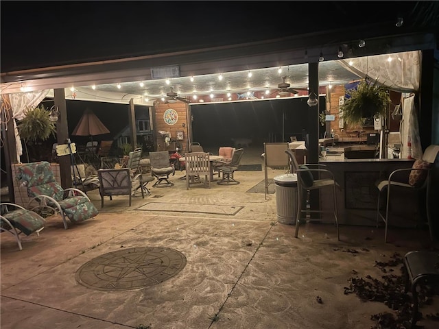 patio at night featuring an outdoor bar and ceiling fan