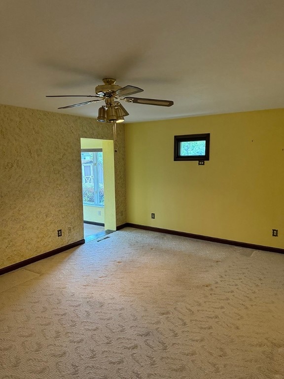 empty room featuring a wealth of natural light, ceiling fan, and carpet