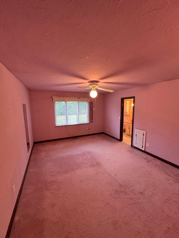 empty room with ceiling fan, a textured ceiling, and light carpet