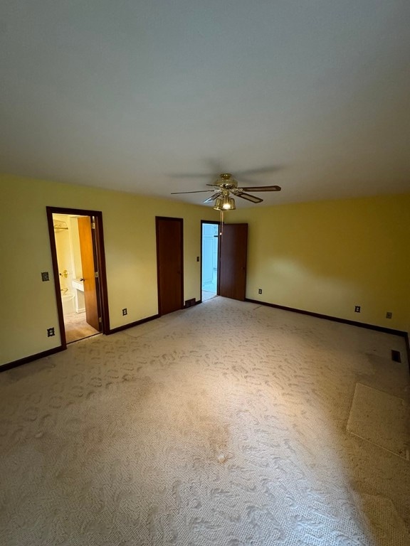 unfurnished bedroom with light colored carpet, ceiling fan, and ensuite bath