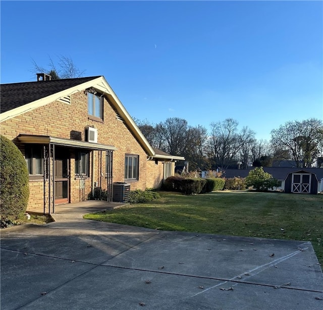 view of home's exterior featuring central air condition unit, a storage unit, and a lawn