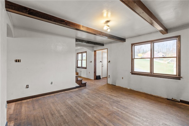 spare room with wood-type flooring and beam ceiling