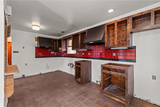 kitchen with wall chimney range hood, backsplash, and dark tile patterned flooring