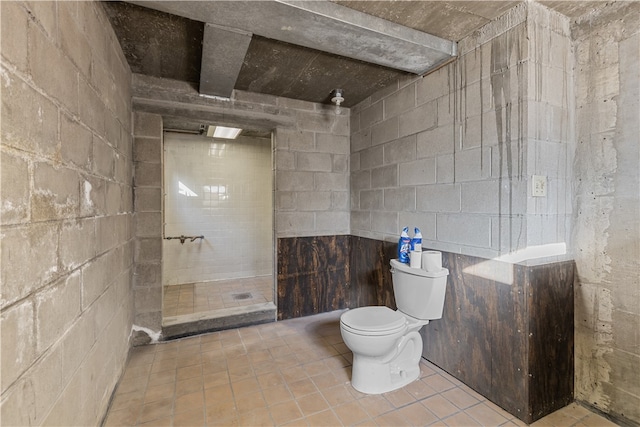 bathroom with walk in shower, toilet, and tile walls