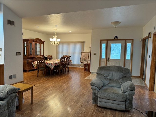 living room with an inviting chandelier, a textured ceiling, and hardwood / wood-style flooring