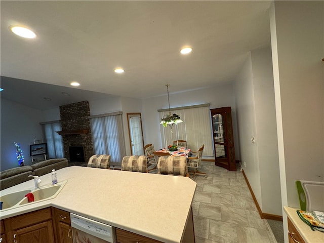 kitchen with a center island, white dishwasher, hanging light fixtures, a fireplace, and a chandelier