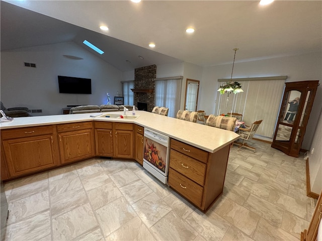 kitchen with dishwasher, sink, hanging light fixtures, vaulted ceiling, and a brick fireplace