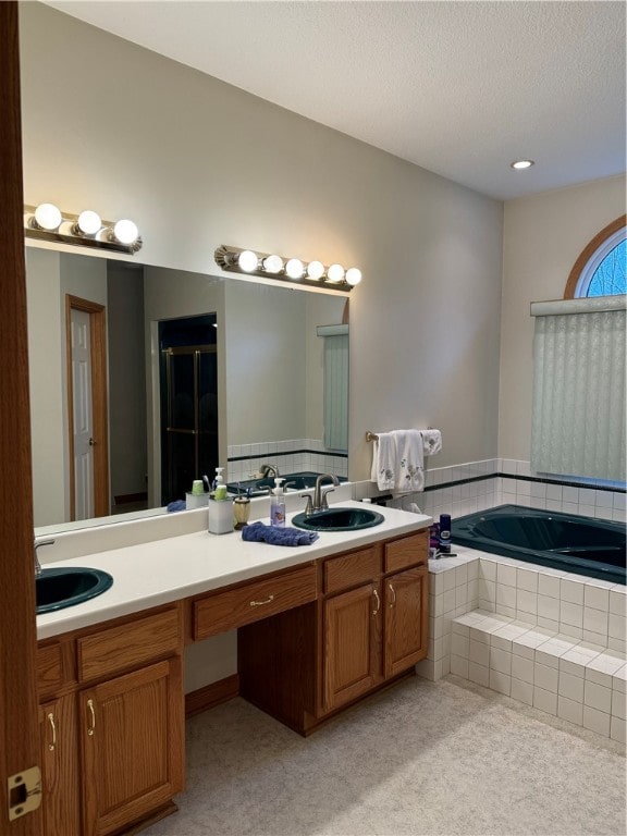 bathroom featuring plus walk in shower, a textured ceiling, and vanity