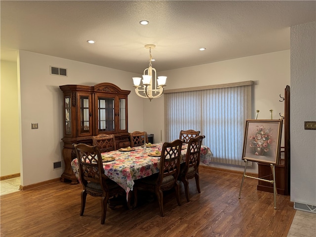 dining room featuring a textured ceiling, hardwood / wood-style flooring, and a notable chandelier