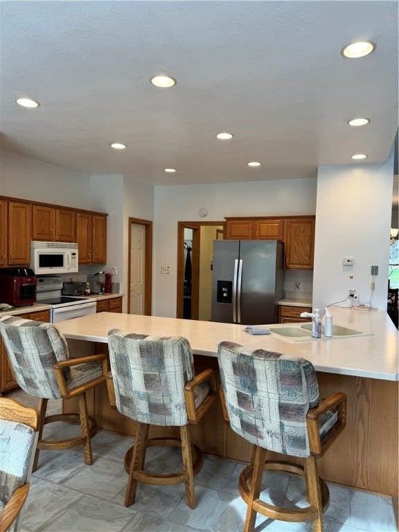 kitchen featuring kitchen peninsula, a kitchen bar, and white appliances