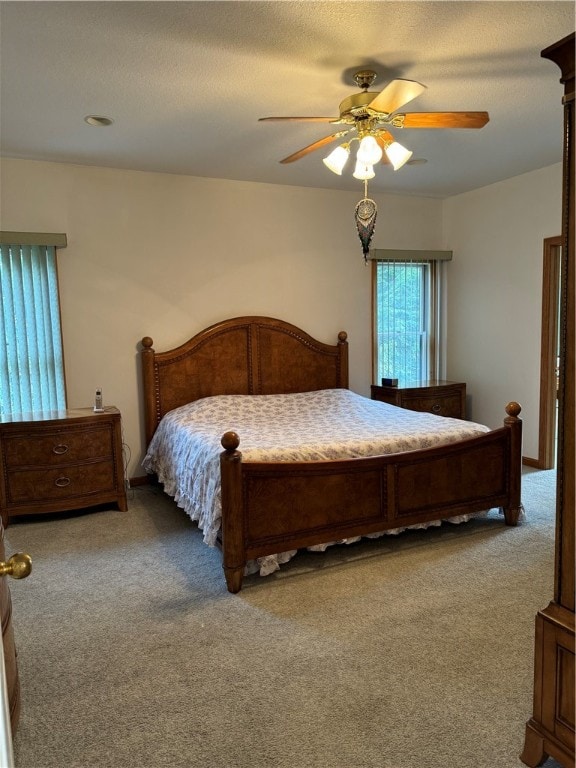 carpeted bedroom featuring ceiling fan and a textured ceiling