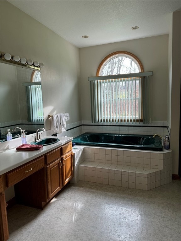 bathroom with vanity and tiled tub