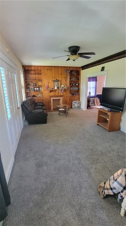 unfurnished living room featuring wooden walls, carpet flooring, and ceiling fan