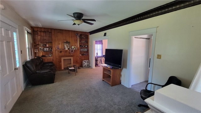 carpeted living room featuring wood walls and ceiling fan