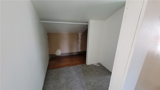 interior space featuring lofted ceiling and dark colored carpet