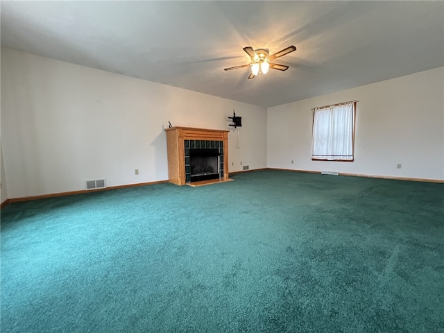 unfurnished living room featuring carpet, a tiled fireplace, and ceiling fan