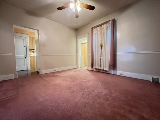 empty room featuring ceiling fan and dark carpet