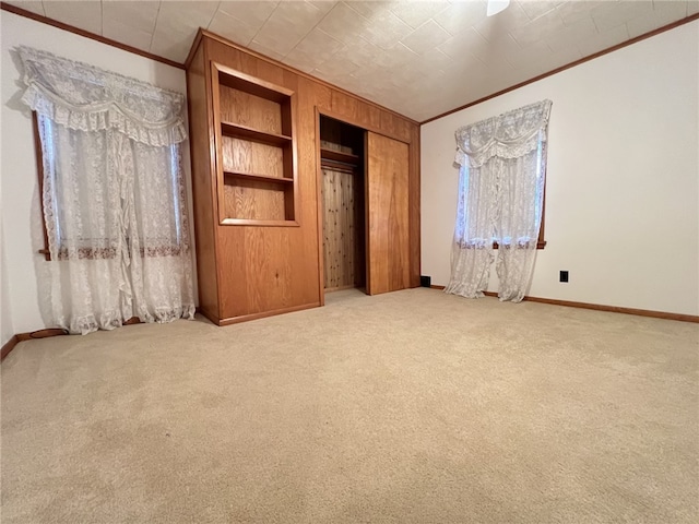 unfurnished bedroom with wooden walls, carpet flooring, and ornamental molding