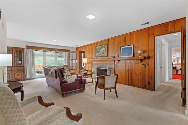 carpeted living room with wooden walls and a brick fireplace