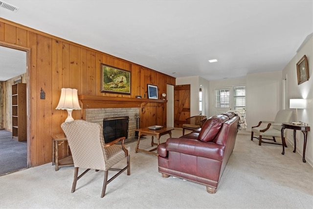 living room featuring a stone fireplace, wood walls, and light carpet