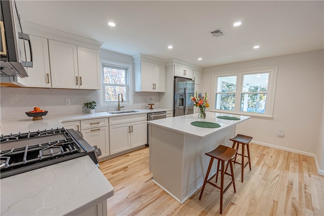 kitchen featuring light hardwood / wood-style floors, sink, appliances with stainless steel finishes, and a center island