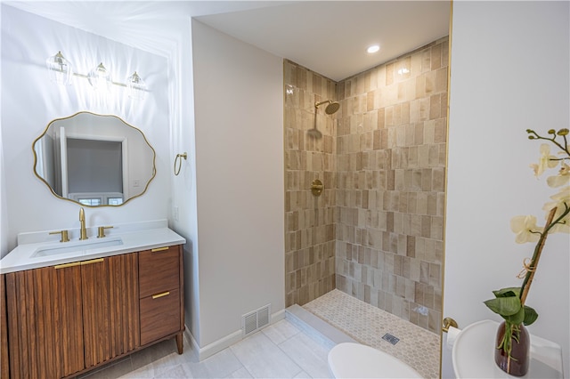 bathroom featuring toilet, vanity, tile patterned floors, and tiled shower