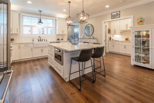 17 Carolina Ave, Oakmont, PA 15139 - kitchen with stainless steel microwave, white cabinetry, a kitchen breakfast bar, crown molding, and a chandelier