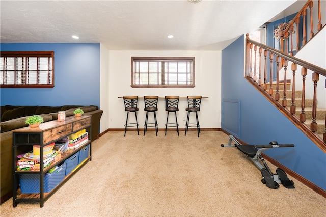 rec room with a textured ceiling, bar, and carpet floors