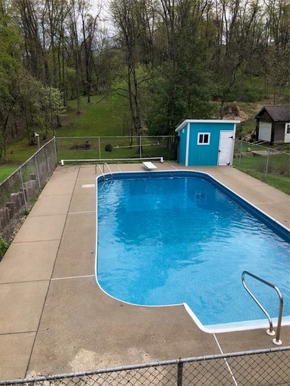 view of swimming pool featuring a diving board and a storage shed