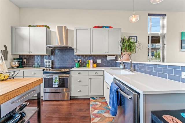 kitchen featuring stainless steel appliances, dark hardwood / wood-style floors, decorative light fixtures, wall chimney range hood, and decorative backsplash