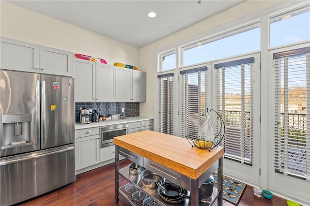 kitchen featuring a wealth of natural light, appliances with stainless steel finishes, dark hardwood / wood-style floors, and tasteful backsplash