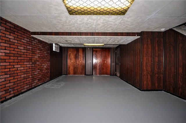 basement featuring wood walls and brick wall