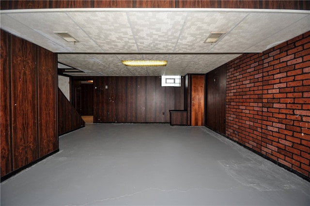 basement featuring wooden walls and brick wall