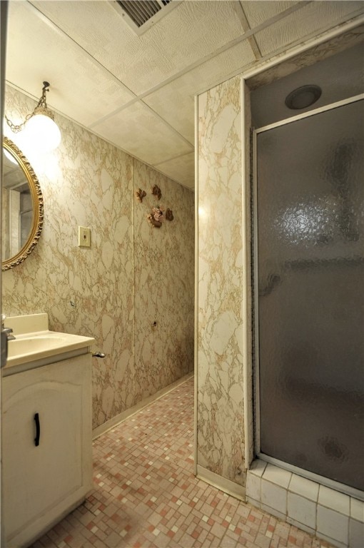 bathroom featuring vanity, a drop ceiling, and a shower