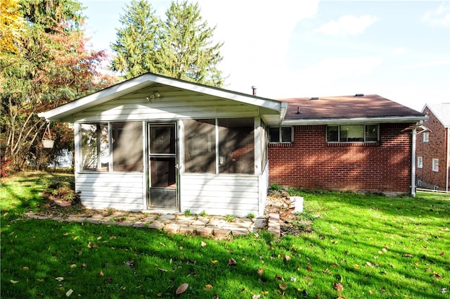 back of property with a lawn and a sunroom