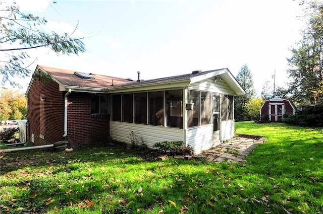 view of side of home featuring a sunroom, a yard, and a storage shed