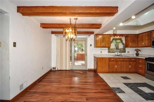 kitchen with stainless steel appliances, a notable chandelier, hanging light fixtures, beam ceiling, and light wood-type flooring