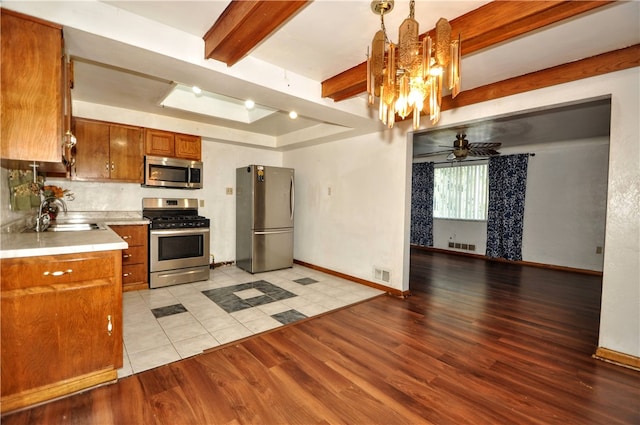 kitchen featuring ceiling fan with notable chandelier, light hardwood / wood-style flooring, hanging light fixtures, beam ceiling, and appliances with stainless steel finishes