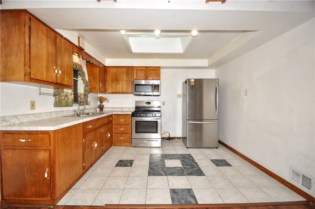 kitchen with stainless steel appliances, light tile patterned flooring, sink, and a skylight