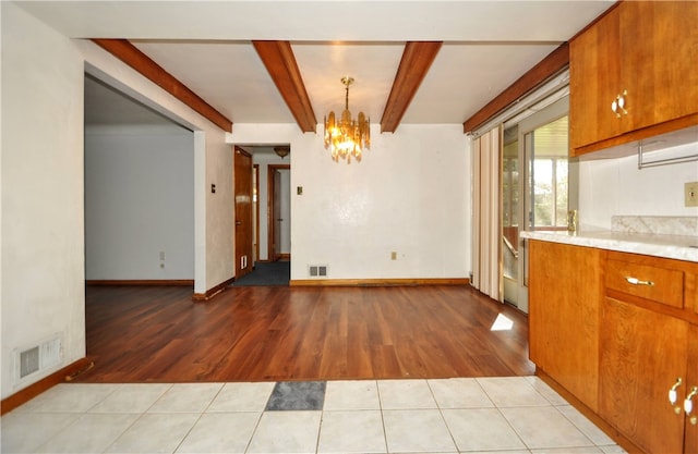 unfurnished dining area featuring light hardwood / wood-style flooring, a notable chandelier, and beamed ceiling