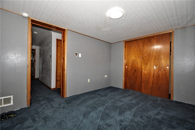 unfurnished bedroom featuring a closet, a textured ceiling, and dark colored carpet