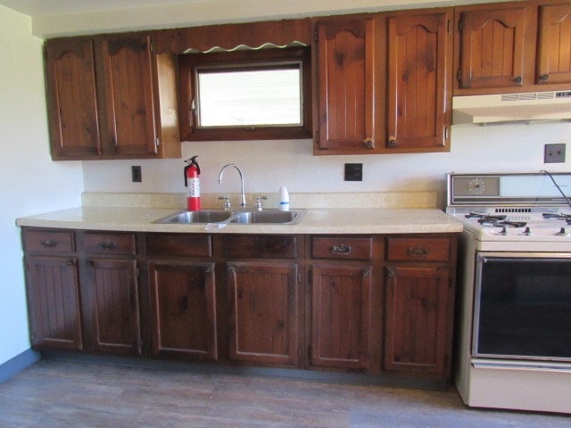 kitchen with white stove, dark hardwood / wood-style flooring, and sink