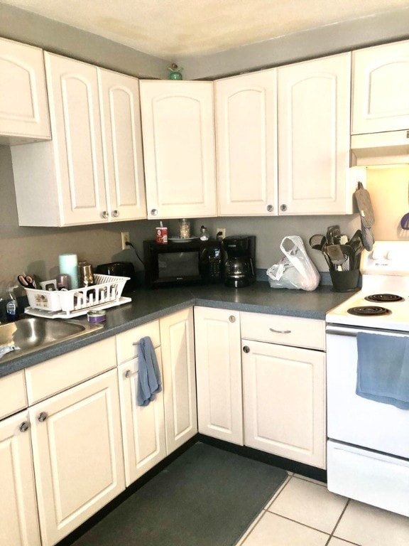 kitchen featuring white electric stove, sink, light tile patterned floors, and white cabinets