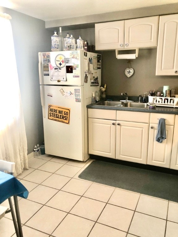 kitchen with white cabinetry, light tile patterned floors, sink, and white refrigerator