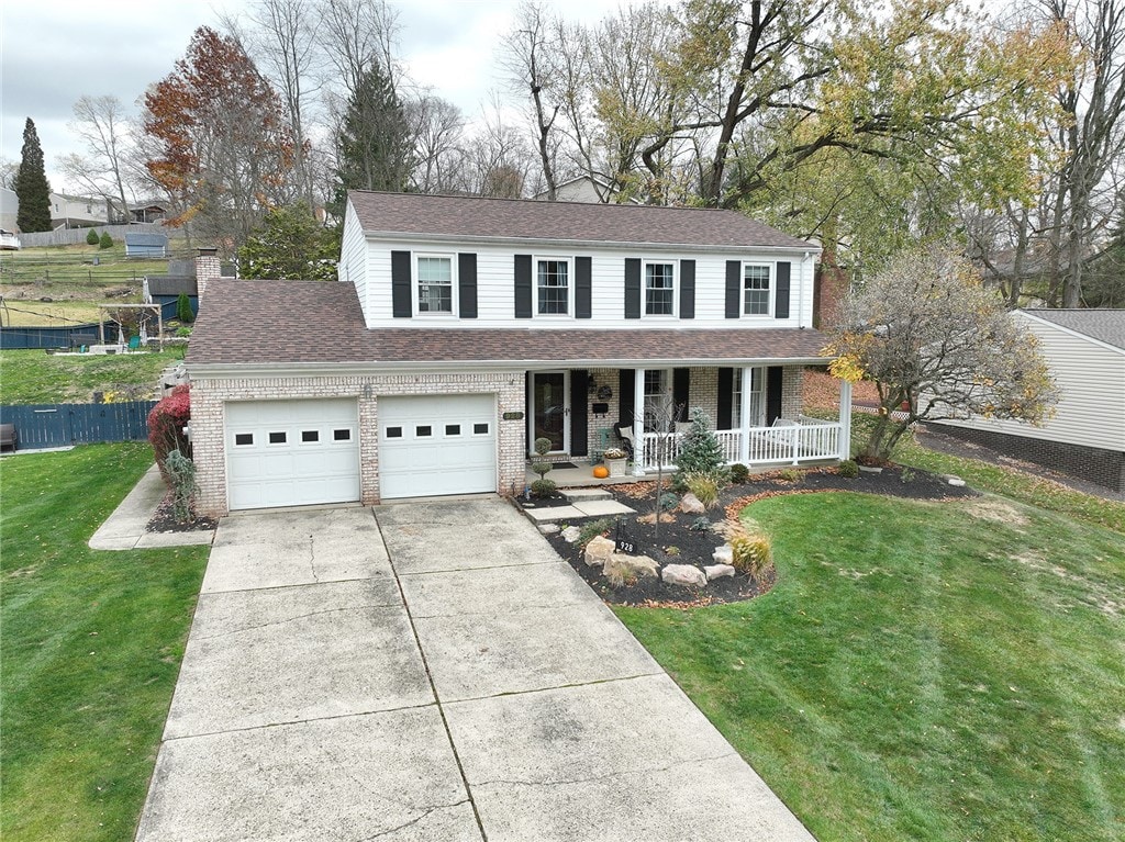 view of front of property featuring a front lawn, a garage, and covered porch